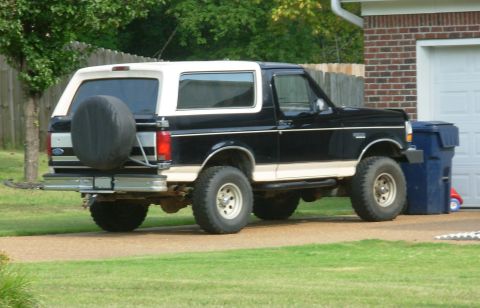 1983 Ford Bronco - This Ford Bronco is parked in a driveway next to a blue trash bin and a garage.