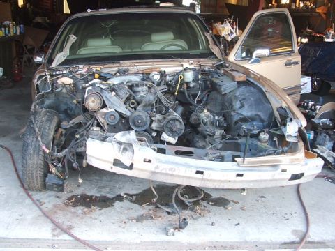 1966 Ford Ranchero - The front of a tan car is disassembled, revealing the engine and surrounding components.