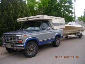 1983 Ford Bronco - This 1980s Ford Bronco is equipped with a camper shell and tows a boat on a trailer.