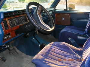 1983 Ford Bronco - The interior of a classic Ford Bronco, blue upholstery and wood-grain trim on the dashboard.