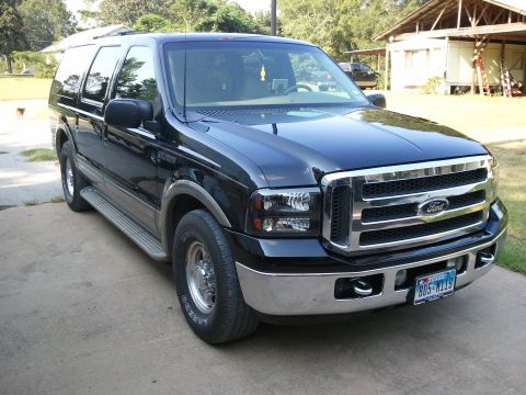 2001 Ford Excursion - This 2001 Ford Excursion is parked outside a building with trees in the background.
