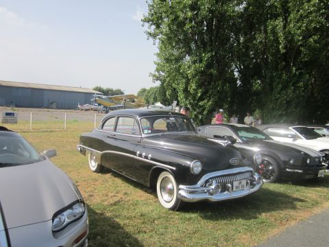 1991 Ford LTD Crown Victoria - A black 1953 Buick Special sedan is parked on grass at an outdoor event with airplanes in the background.