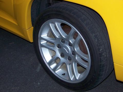 2005 Chevrolet Colorado - Close-up of a yellow truck's front wheel, a silver five-spoke rim with a Chevrolet badge visible in the center.