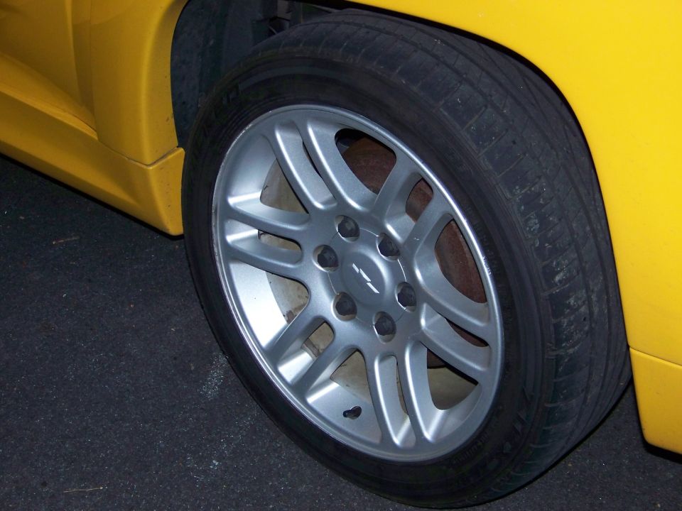 Yellow truck wheel with silver five-spoke rim and visible Chevrolet badge