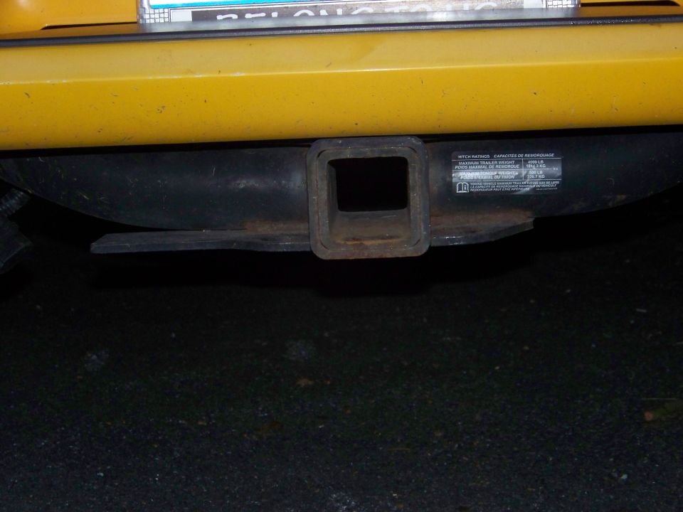 Yellow vehicle bumper with trailer hitch receiver and warning label
