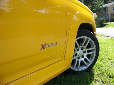 2005 Chevrolet Colorado - A yellow pickup truck is parked on grass, with a house visible in the background.