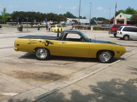 1972 Ford Ranchero - A yellow 1972 Ford Ranchero with a black hood and bed cover is parked in a lot.