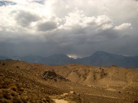 1996 Ford Bronco - A vast desert scene unfolds with arid terrain and imposing mountains beneath a dramatic, cloud-filled sky.