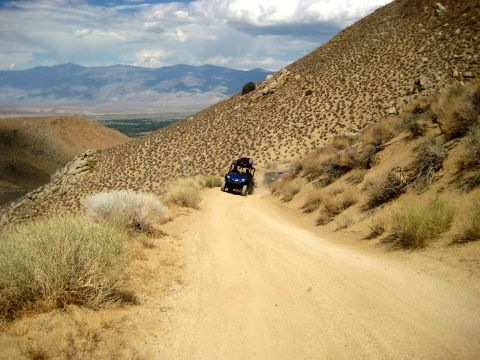 1996 Ford Bronco - Off-road vehicles ascend a steep, dusty trail through a dry, mountainous landscape.