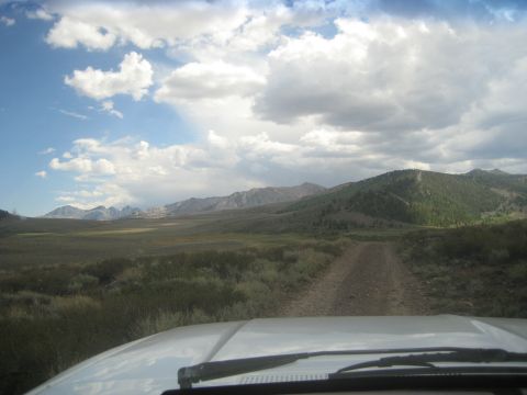 1996 Ford Bronco - Driving on a dirt road through a vast, open landscape with mountains on the horizon.