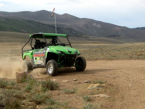 1996 Ford Bronco - A green UTV navigates a dusty trail in a mountainous, arid landscape.