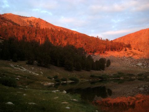 1996 Ford Bronco - A mountain landscape is illuminated by the warm glow of sunset, with trees and a lake in the foreground.