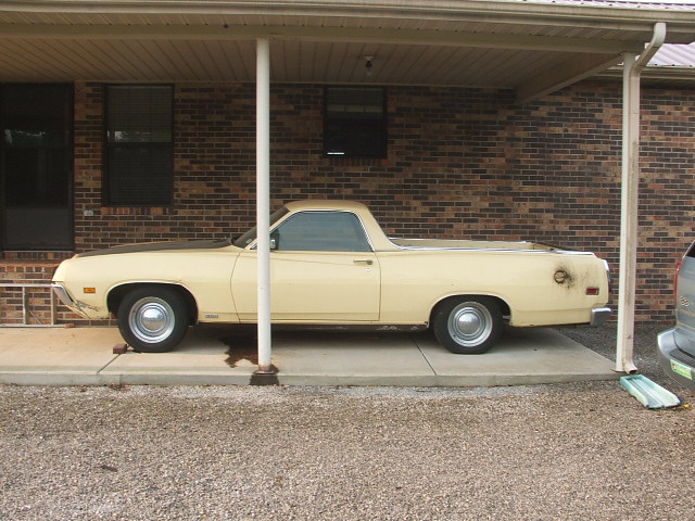 Yellow 1972 Ford Ranchero side view parked under a carport