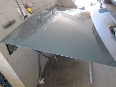 1991 Ford LTD Crown Victoria - A gray car hood is shown from an angle, resting on metal supports in what appears to be a workshop.