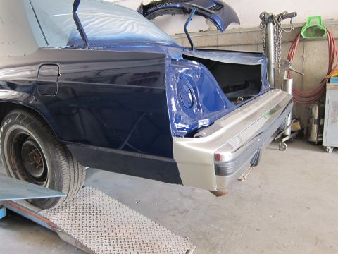 1991 Ford LTD Crown Victoria - Rear of a 1991 Ford Crown Victoria LTD in a body shop, with the trunk open and parts of the bumper replaced.