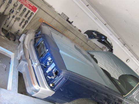 1991 Ford LTD Crown Victoria - Interior view of a blue car undergoing repairs, with a parts chart visible on the wall.