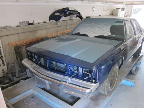 1991 Ford LTD Crown Victoria - A dark blue Ford Crown Victoria is in a garage, undergoing repairs with its front end disassembled.