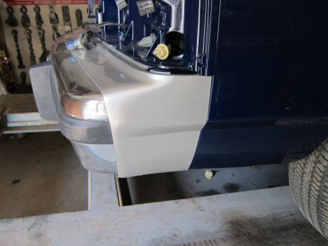 1991 Ford LTD Crown Victoria - Close-up of a dark blue vehicle's rear quarter panel and bumper corner, with a section of grey primer visible.
