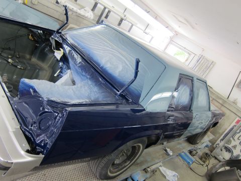 1991 Ford LTD Crown Victoria - A car is being worked on in a garage, with parts of it covered in plastic sheeting.