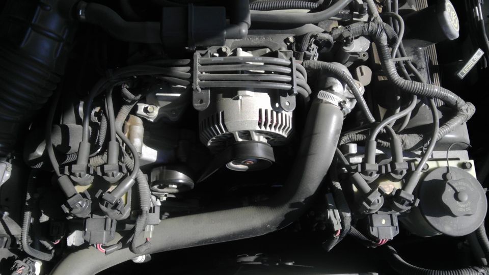 Engine bay shot showing alternator, spark plug wires, and hoses. Supermotors.net logo visible