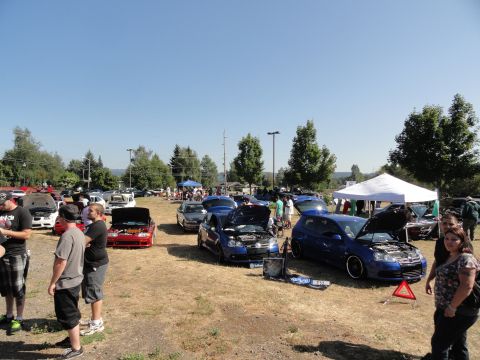 1964 Ford Fairlane - Attendees gather around various vehicles, some with hoods open, at an outdoor car show event.