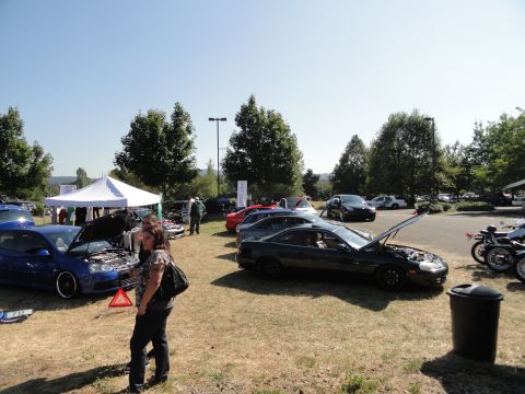 1964 Ford Fairlane - An outdoor gathering of vehicles and attendees, with multiple cars on display under a clear sky.