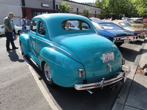 1964 Ford Fairlane - A teal coupe with a distinctive body style is parked next to other vehicles.