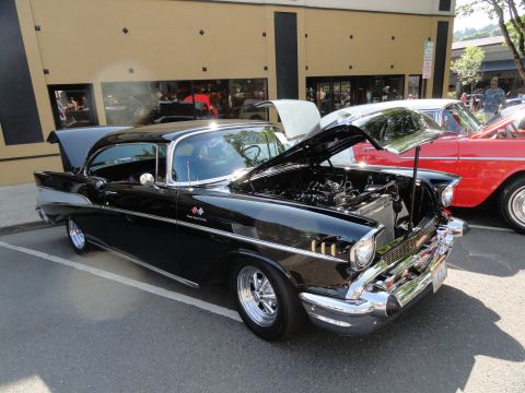 1964 Ford Fairlane - Two classic cars, a black 1957 Chevrolet Bel Air and a red car, are parked side-by-side.
