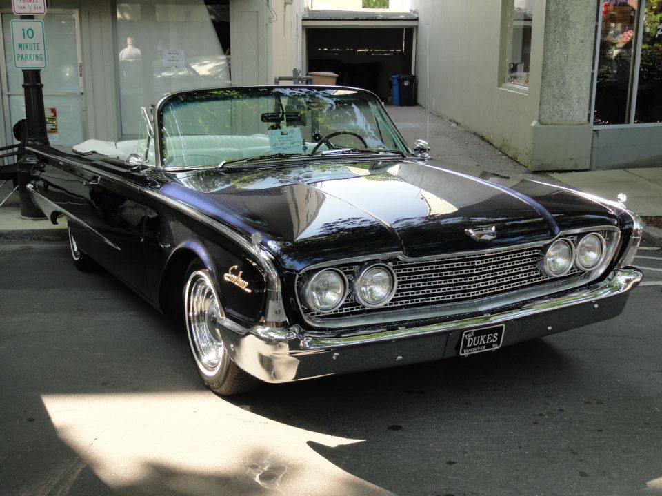 Black 1960 Ford Starliner convertible parked on street, front quarter view. License plate says 'DUKES'