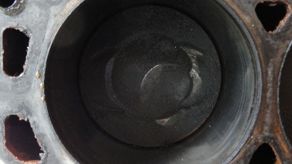 Close-up of an engine cylinder showing a piston top with carbon buildup
