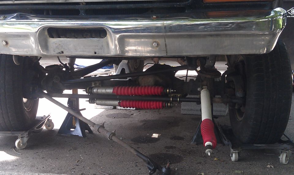 Front suspension components with red shock absorbers and chrome bumper above