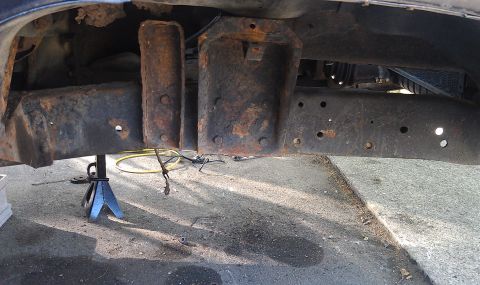1979 Ford Bronco - Rusted vehicle frame and suspension components are visible, supported by a jack stand.