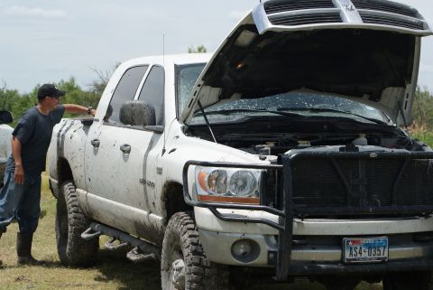 1989 Ford Bronco - White Dodge Ram pickup truck with hood open, a man inspects the engine bay. Mud splatters visible on the body.