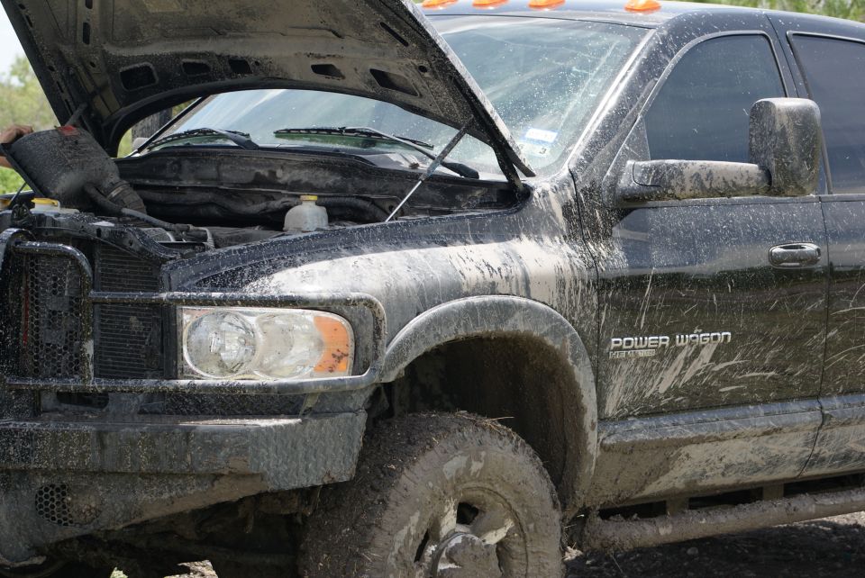 Black Dodge Power Wagon with hood open, covered in mud
