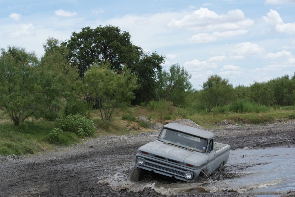 Gray 1965 Chevrolet C10 pickup truck driving through a muddy track