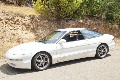 1993 Ford Taurus - A white Ford Probe GT is parked on the side of a road with a natural landscape behind it.