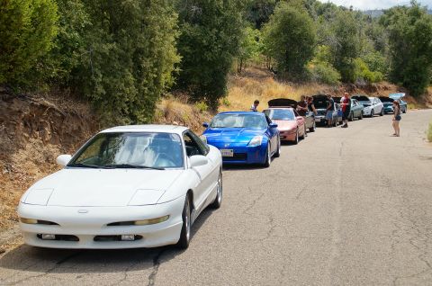 1993 Ford Taurus - A group of cars are lined up on a road, with people gathered around them.