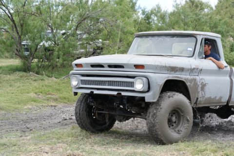 1989 Ford Bronco - This vintage pickup truck, likely from the mid-1960s, navigates muddy terrain with its oversized tires. Another vehicle is visible in the b…