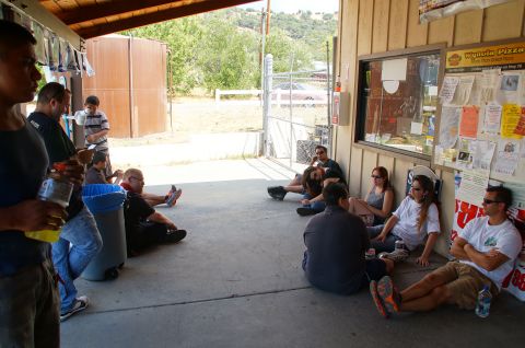 1993 Ford Taurus - A group of people are gathered on a patio outside a building, some sitting on the ground and others leaning against the wall.