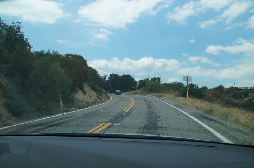 Car driving on a winding road with trees and a cloudy sky