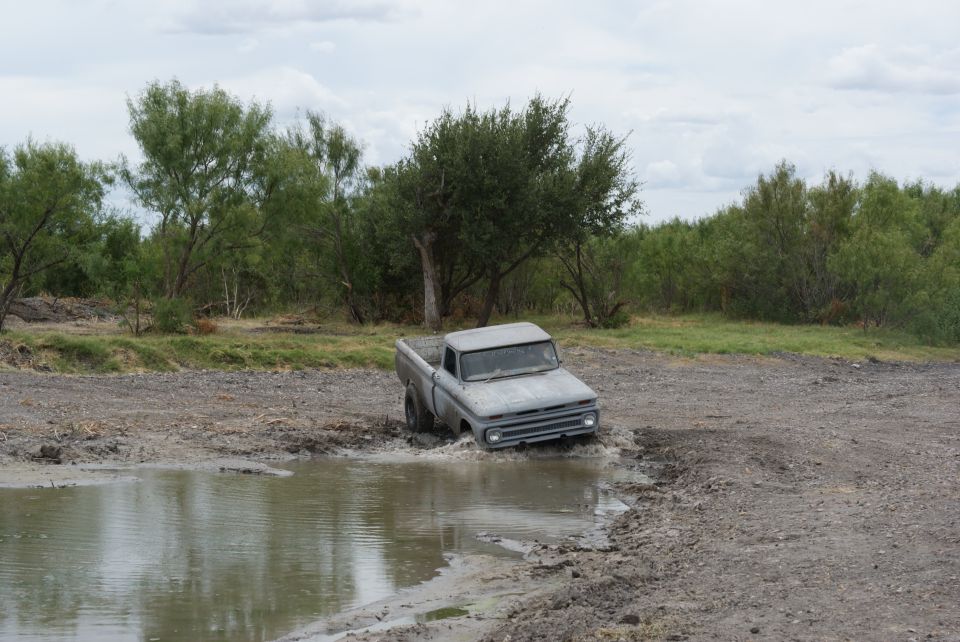 Gray pickup truck stuck in mud puddle, front view