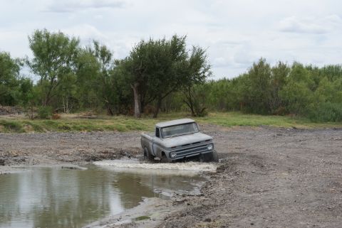 1989 Ford Bronco - Classic Chevrolet C10 pickup truck struggles through a muddy off-road obstacle.