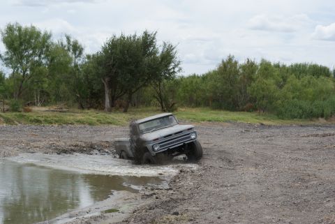 1989 Ford Bronco - This vintage pickup truck is navigating a challenging muddy terrain.
