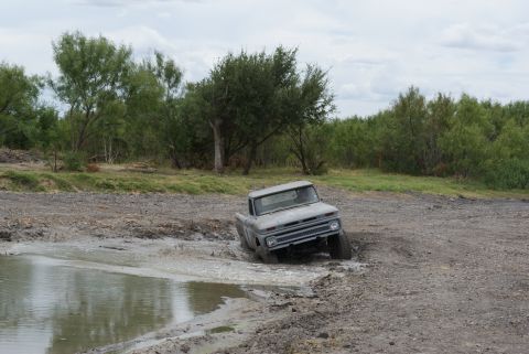 1989 Ford Bronco - A vintage gray pickup truck navigates a muddy obstacle course.