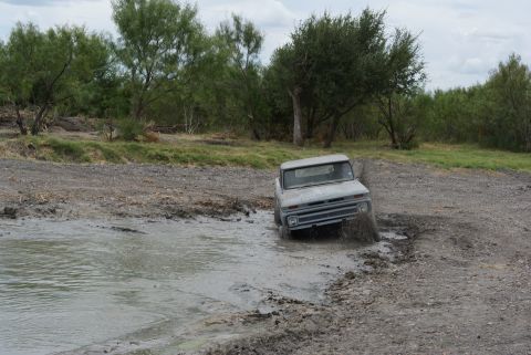 1989 Ford Bronco - This vintage pickup truck navigates a muddy terrain, kicking up water and dirt.