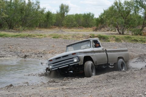 1989 Ford Bronco - This vintage pickup truck navigates a muddy terrain, kicking up water and dirt.