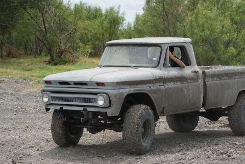 1989 Ford Bronco - This vintage pickup truck appears to be off-roading in a rural area.