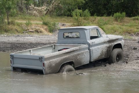 1989 Ford Bronco - This 1965 Chevrolet C10 is stuck deep in the mud, with only its front right tire visible.