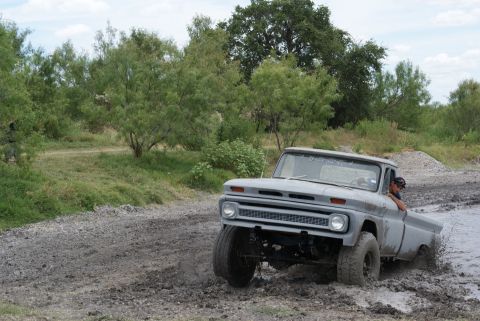 1989 Ford Bronco - This gray pickup truck, likely a 1966 model, navigates a muddy terrain.