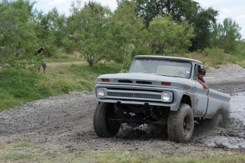 1989 Ford Bronco - This vintage pickup truck is navigating a muddy terrain, with a photographer visible in the background.